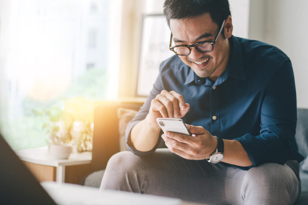 Man with glasses on phone comparing insurance quotes from Quaint Oak Insurance