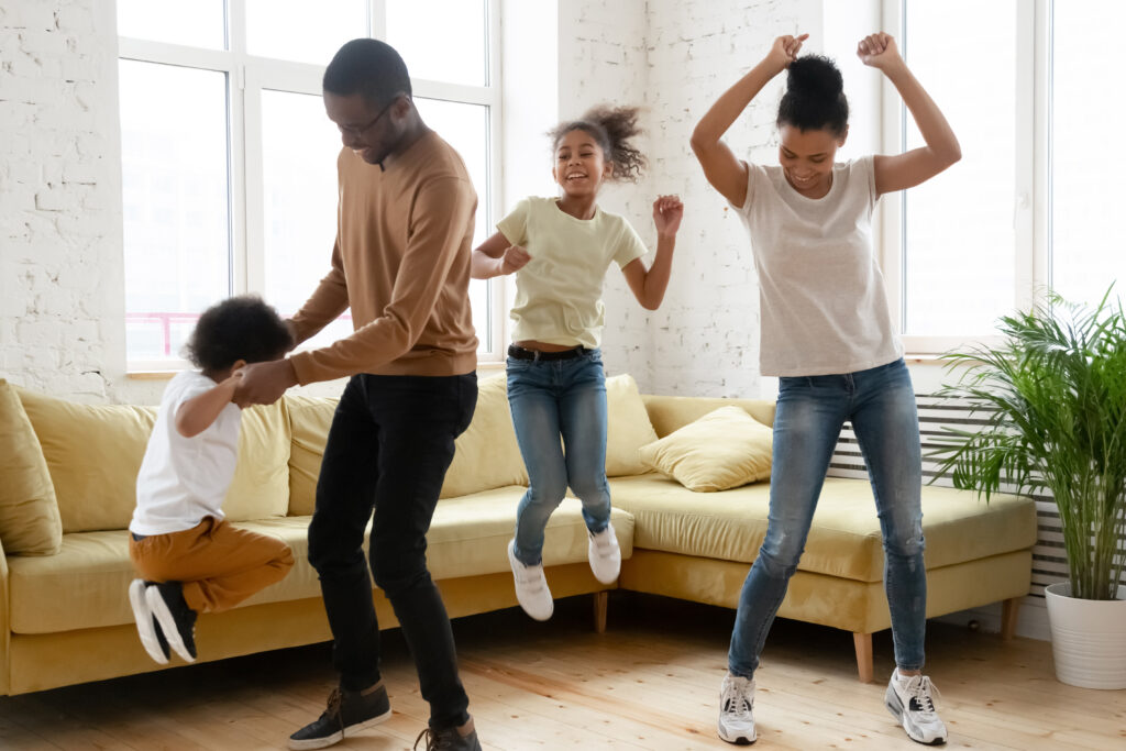 Family happily dancing in their living room after purchasing a policy after learning more about what is umbrella insurance